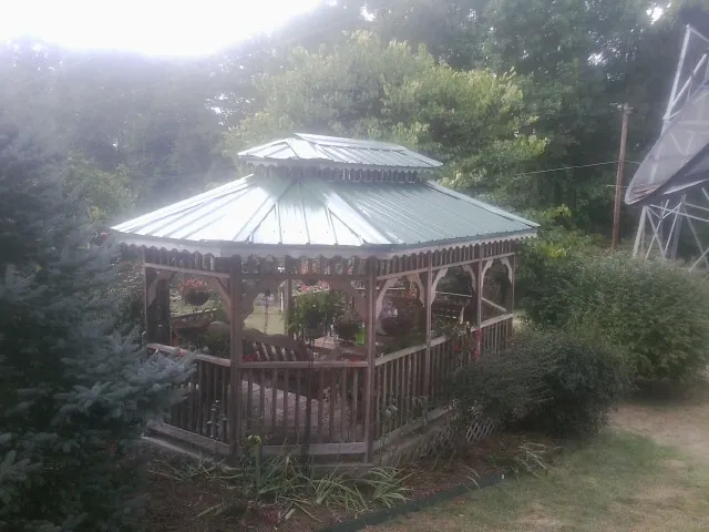 Green metal roof on a backyard gazebo surrounded by garden beds in Cherry Valley