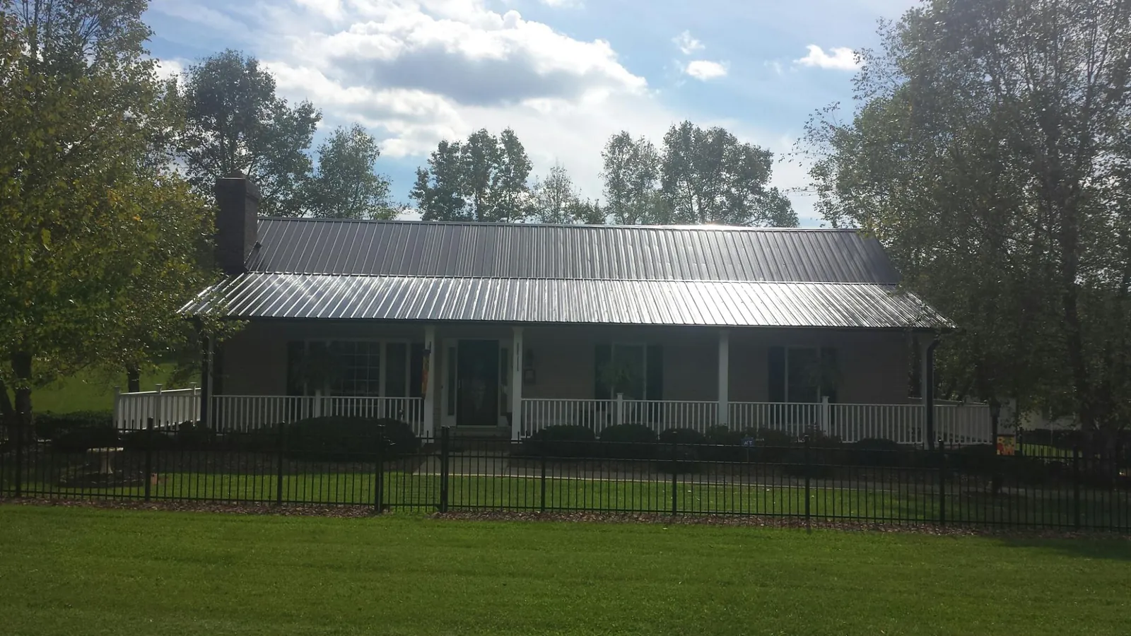 Gray metal roof on a brick ranch with a full width front porch — Gutter Guard Installation work by our crew in Cherry Valley